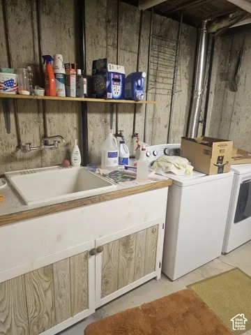 Utility area featuring a drop-in basin sink, wall-mounted faucet, wood-finish cabinet cabinetry, and a mounted wall shelf