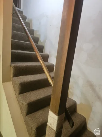 Staircase featuring wall-to-wall carpeting and a wooden handrail