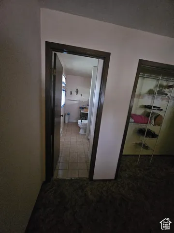 Interior doorway with dark-toned trim, tiled floor, and a built-in wire closet shelving system