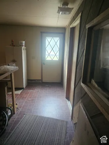 Interior space featuring square tile flooring, diagonal wood-panel wall treatments, a flush-mount ceiling fixture, and a diamond-grid glass pane door