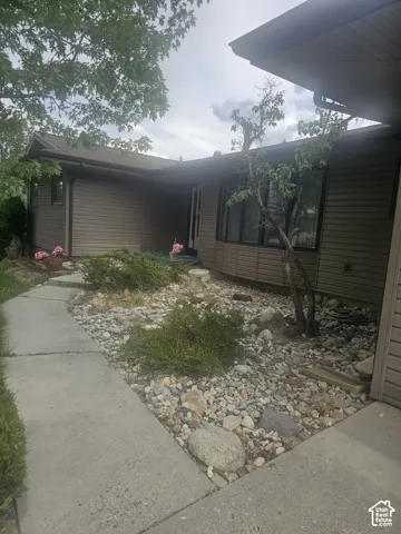 Exterior featuring horizontal siding, a bay window, concrete walkway, and low-maintenance rock landscaping
