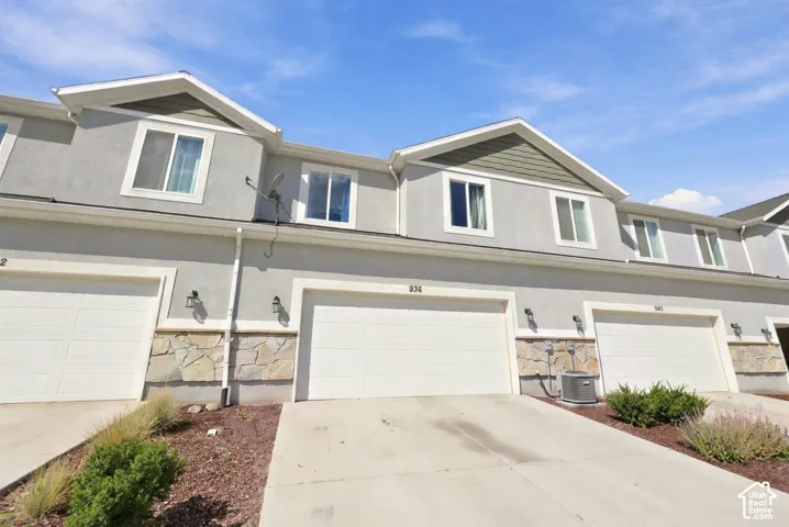 Multi-level exterior featuring stucco and stone facade, attached two-car garages, and double-hung windows
