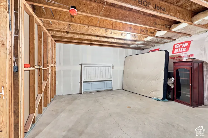 Unfinished lower-level space featuring exposed wood-joist ceiling, concrete flooring, and partial drywall installation
