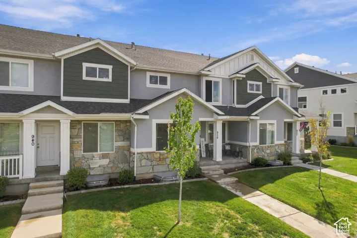 Multi-unit residential exterior featuring mixed-material siding, stacked stone veneer accents, gabled rooflines, and covered front entry porches