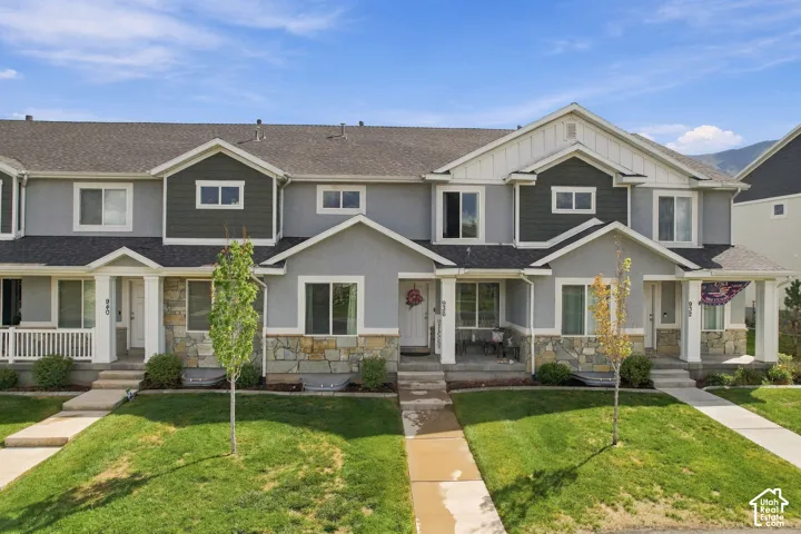 Multi-unit exterior featuring composite shingle roofing, stone veneer cladding, vertical siding accents, and covered front porches with structural columns