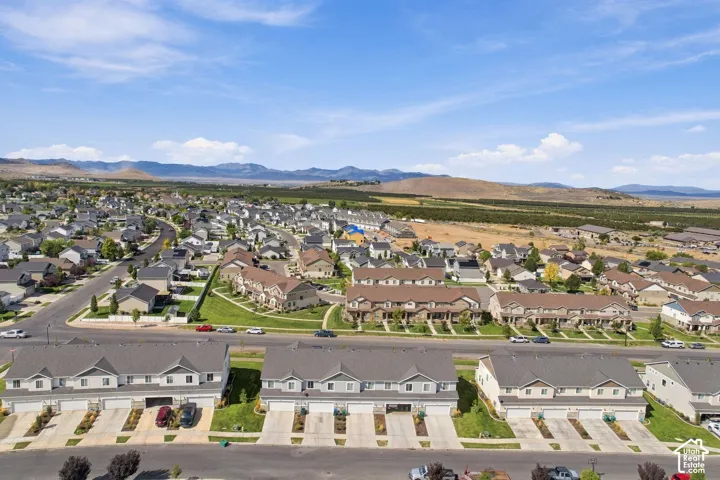 Aerial perspective of residential community featuring multi-unit dwellings with attached garages, concrete driveways, and mountain backdrop