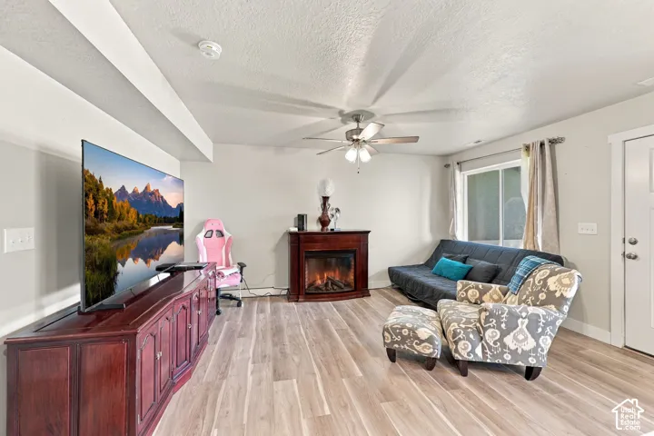 Neutral wall tones, wood-finish flooring, ceiling fan with integrated lighting, and sliding glass window
