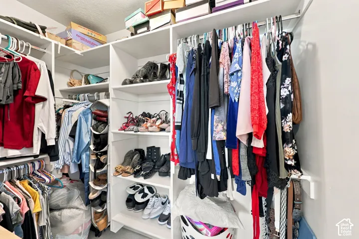 Custom walk-in closet featuring white built-in shelving, multiple hanging rods, and integrated storage cubbies