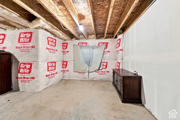 Unfinished space featuring exposed timber joists and a concrete floor
