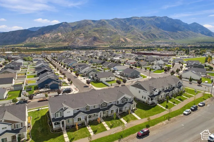 Aerial perspective of multi-story residential dwellings featuring dark asphalt shingle roofing, contrasting lap siding, and stone veneer accents, set against a prominent mountain backdrop