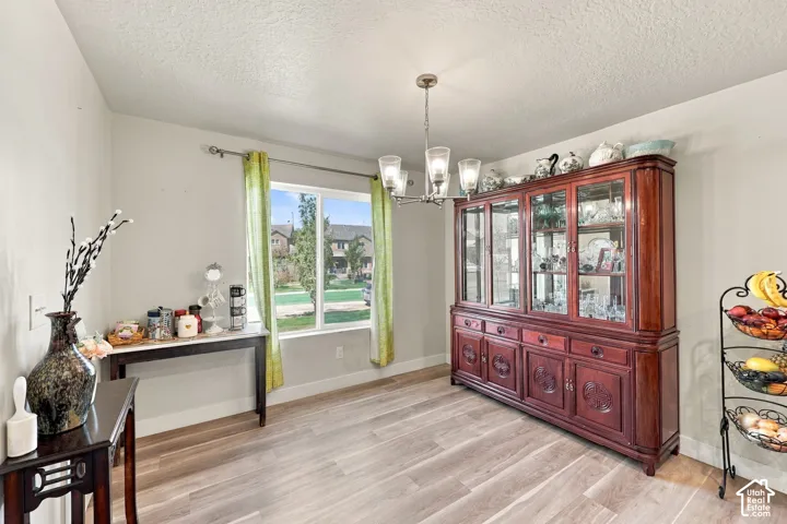Wood-finish flooring, multi-light chandelier, and large window