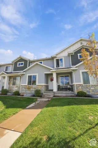 Multi-level exterior featuring a combination of stone veneer and horizontal siding, covered front porch, and manicured lawn