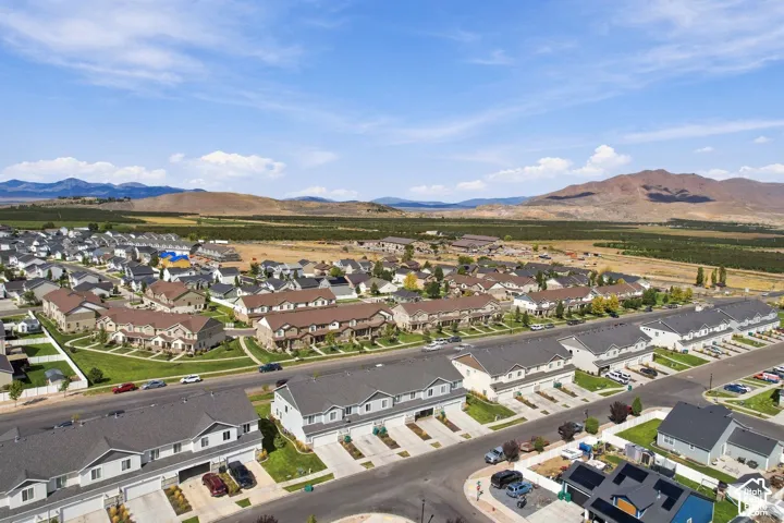 Aerial view of multi-unit residential structures featuring attached garages, paved driveways, and composition shingle roofing, set against a mountainous landscape
