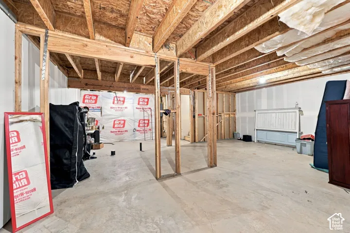 Unfinished basement featuring exposed wood joists, concrete flooring, and framed wall partitions
