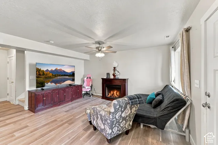 Wood-finish flooring, central ceiling fan with integrated lighting, and neutral wall tones