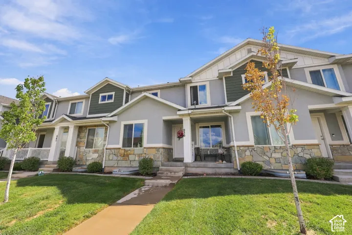Multi-story townhome exterior featuring stone masonry, lap siding, contrasting gable accents, and concrete entry steps