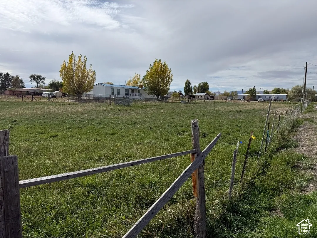 Expansive lot featuring mature trees, peripheral wood and wire fencing, and an open grass field