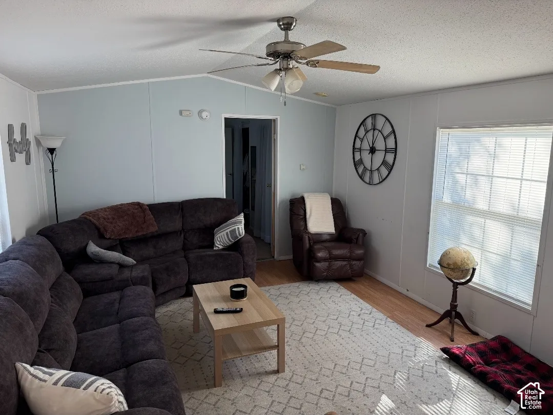 Vaulted ceilings, wood-finish flooring, and a multi-blade ceiling fan with integrated lighting