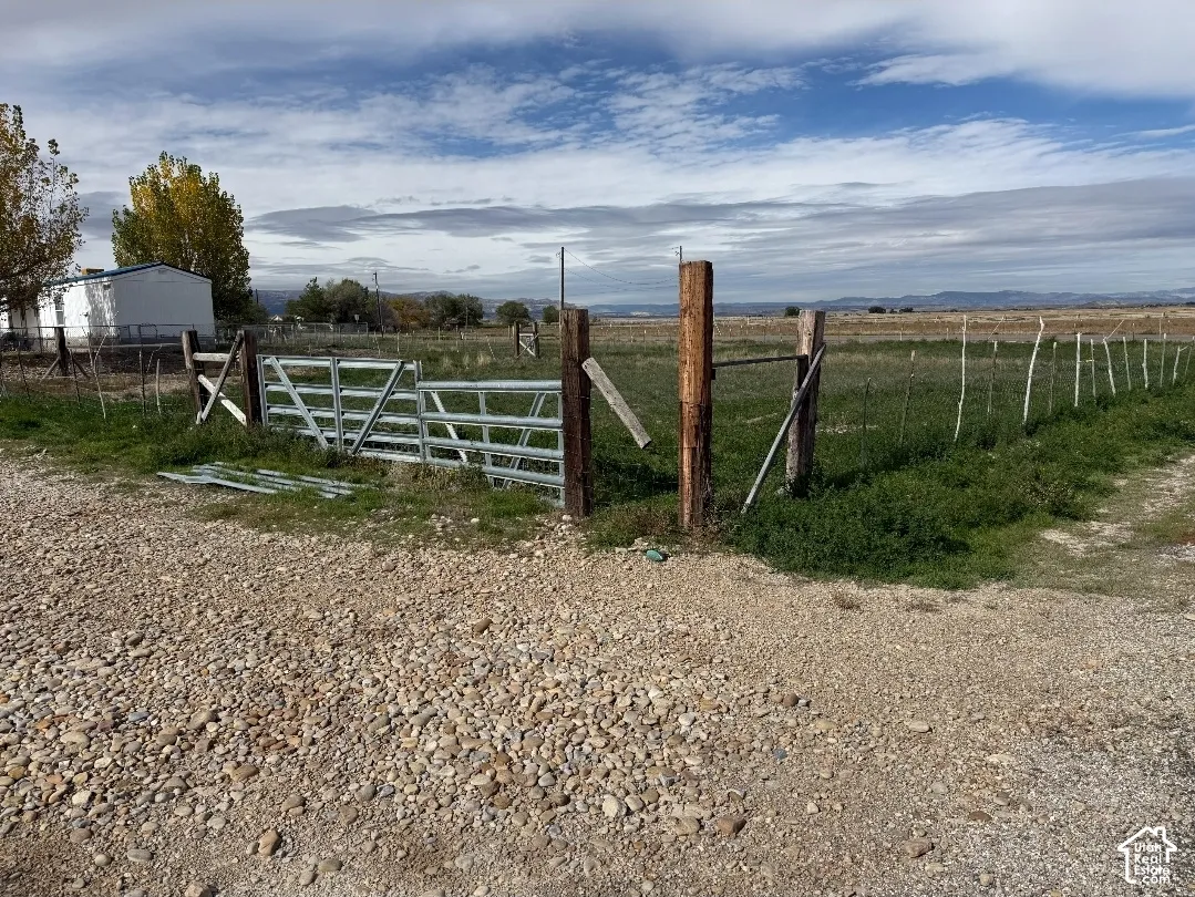 Expansive lot featuring a metal gate entry, timber post fencing, and open terrain with mountain backdrop