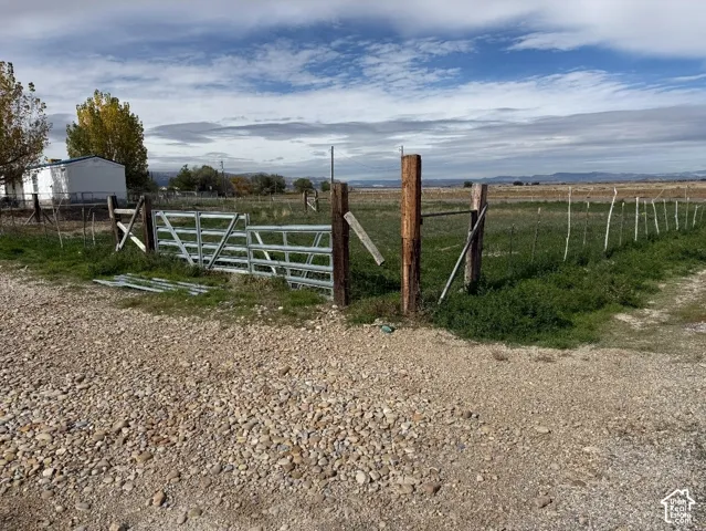 Expansive lot featuring a metal gate entry, timber post fencing, and open terrain with mountain backdrop