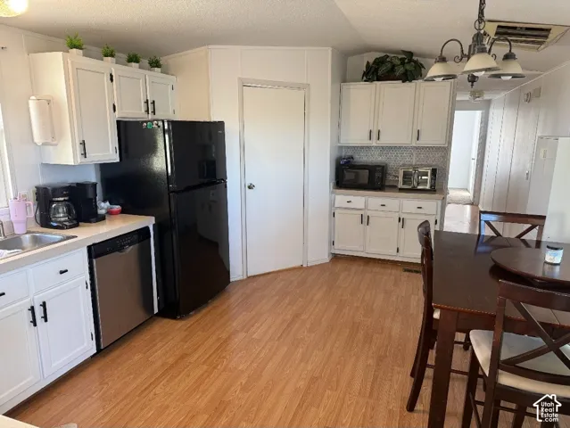 Kitchen featuring white cabinetry with matte black hardware, wood-finish flooring, a stainless steel dishwasher, and a black refrigerator