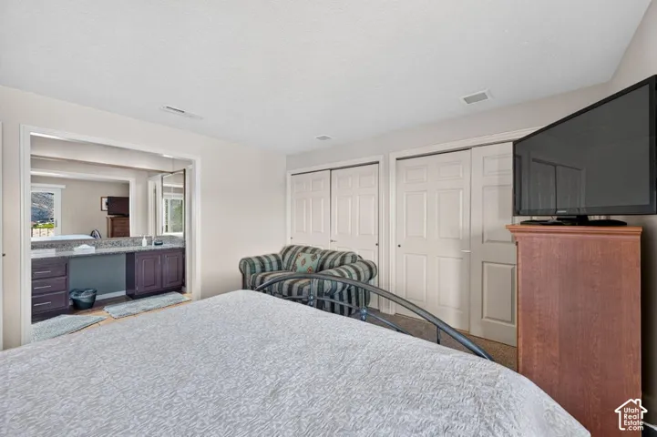 Room featuring two sets of multi-panel closet doors, neutral wall paint, and a built-in vanity with dark wood cabinetry and stone-finish countertop