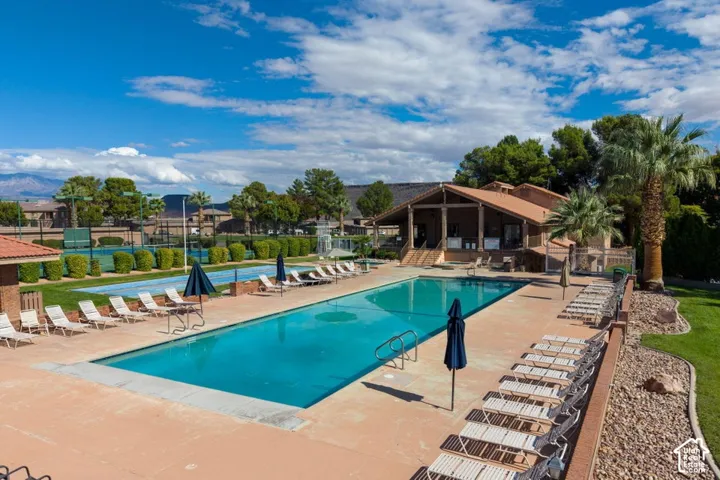Outdoor swimming pool featuring a concrete deck and an expansive, multi-court tennis facility
