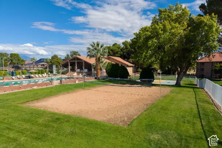 Sand volleyball court featuring a netted perimeter and manicured lawn surroundings
