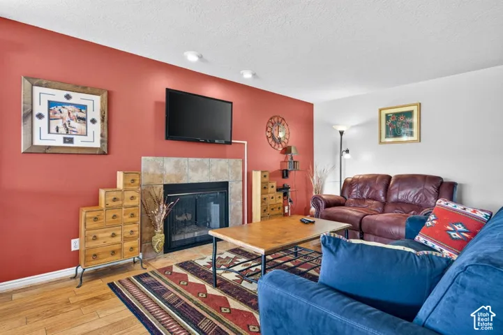 Living area featuring wood-finish flooring, a tile-surround fireplace, and recessed lighting