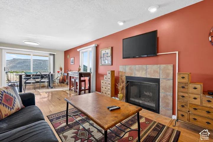 Living area featuring wood-finish flooring, a tile-surround fireplace, recessed lighting, and large sliding glass doors