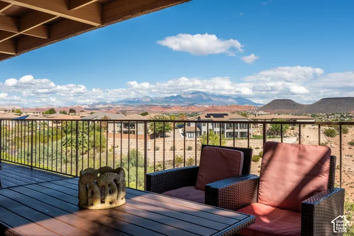 Covered patio featuring an exposed-beam ceiling and a metal railing, overlooking a mountain and desert landscape