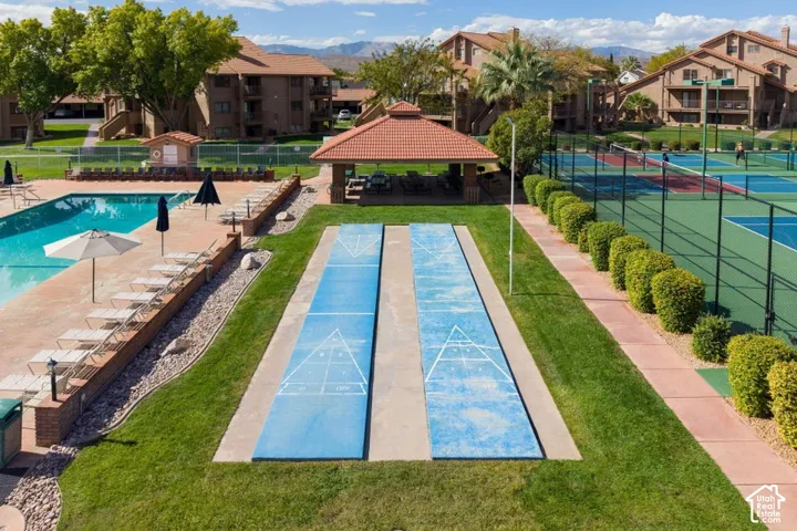 Outdoor recreational area featuring shuffleboard courts, a swimming pool, a covered pavilion with a tiled roof, and tennis courts