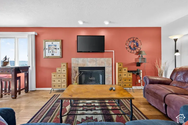 Fireplace featuring tile surround and mantel, wood-finish flooring, and recessed ceiling lighting