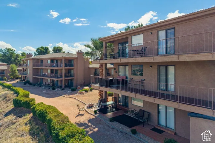 Multi-level complex featuring stucco siding, metal balcony railings, sliding glass doors, and desert-style landscaping