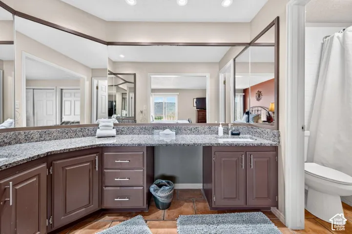 Extended vanity featuring stone-finish countertops, dual integrated sinks, dark wood cabinetry, and a full-width mirror