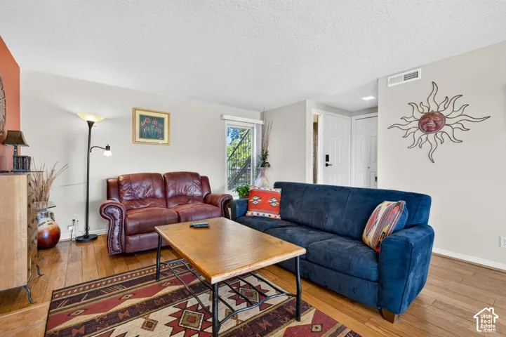 Living area featuring wood-finish flooring, a neutral color palette, and a paneled entry door