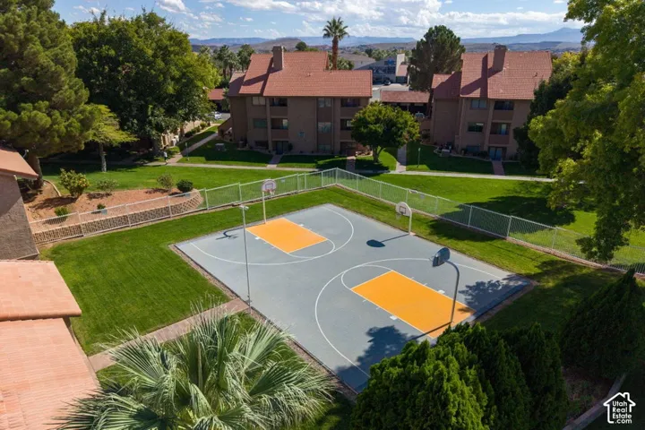 Fenced basketball court with multi-purpose surfacing, manicured lawn areas, mature landscaping, and mountain horizon