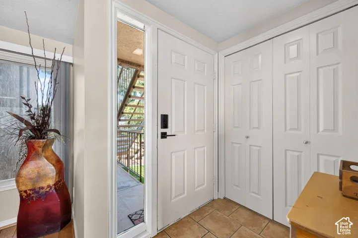 Entryway featuring a white six-panel door with electronic lock, a full-length sidelight, dual-panel closet doors, and ceramic tile flooring