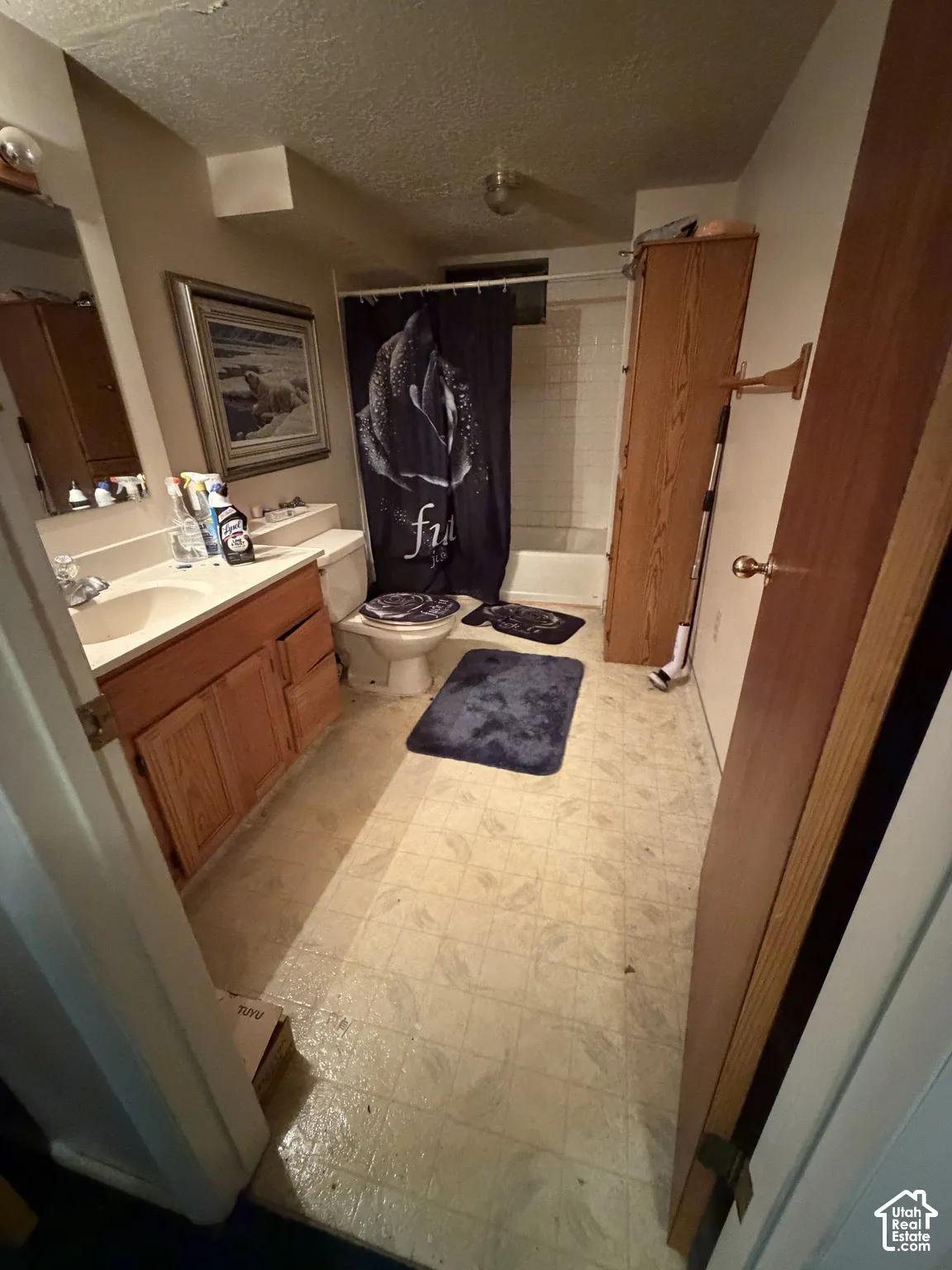 Bathroom featuring a wood-finish vanity with a molded countertop and sink, tub-shower combination with tiled surround, and built-in wood-finish cabinetry