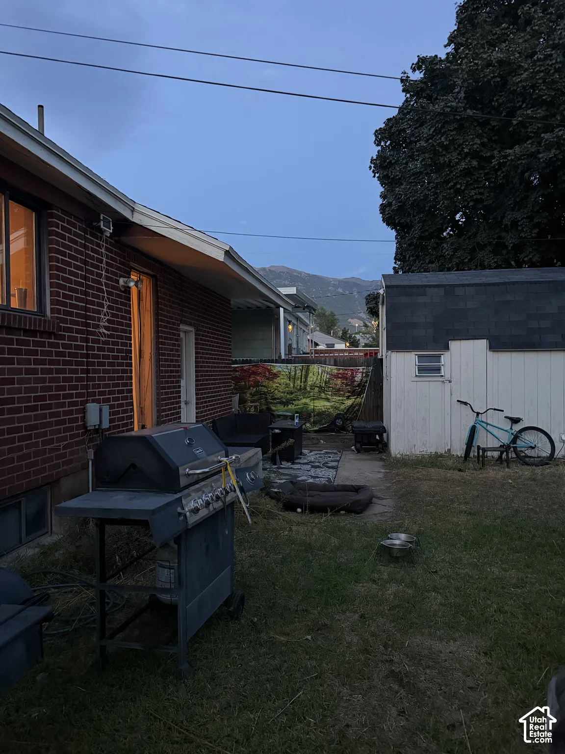Exterior brick siding, standalone storage shed with asphalt shingle roof, and mountain backdrop