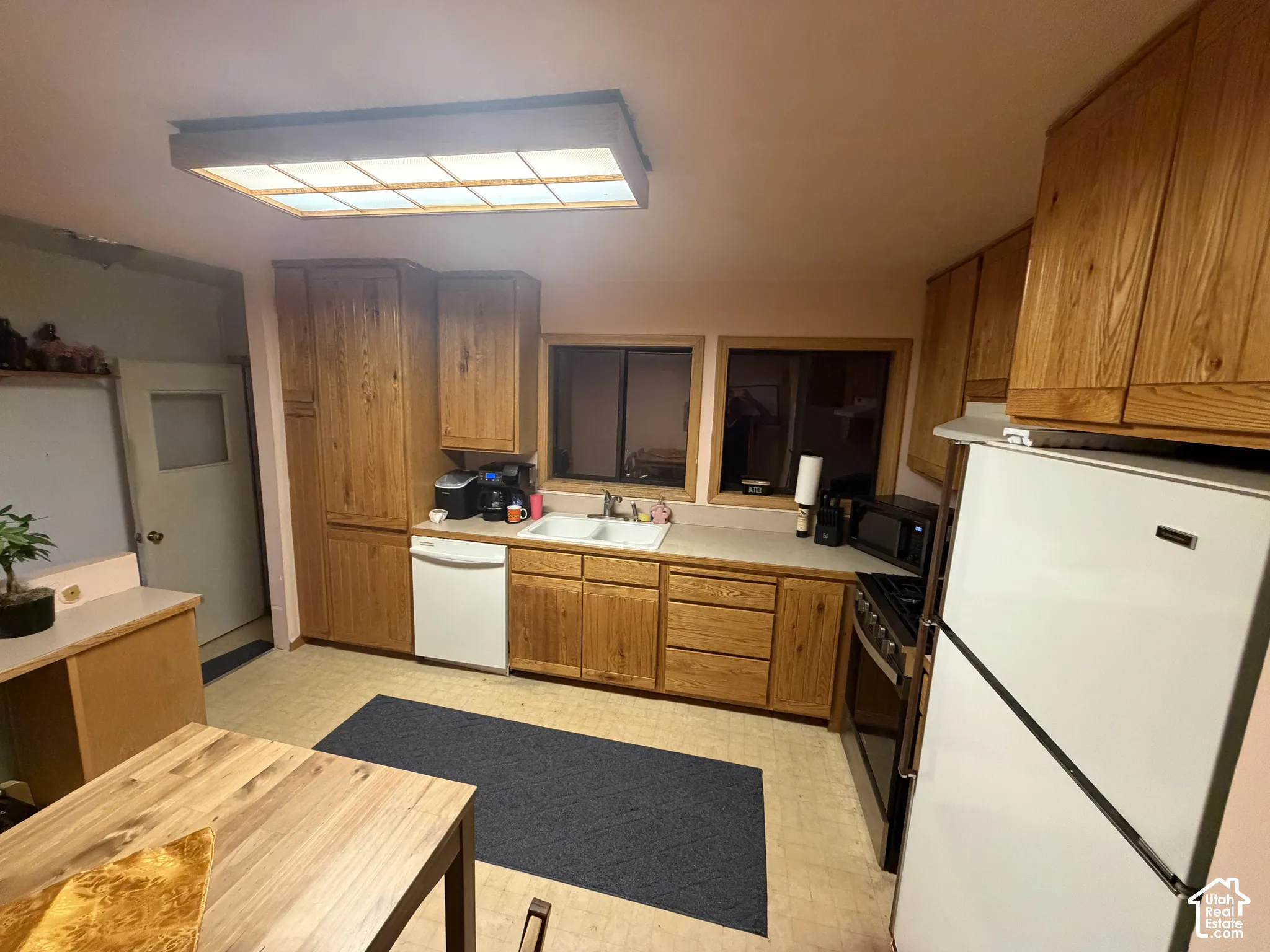 Kitchen featuring wood cabinetry, solid-surface countertops, a double-basin sink, and a rectangular recessed ceiling light fixture