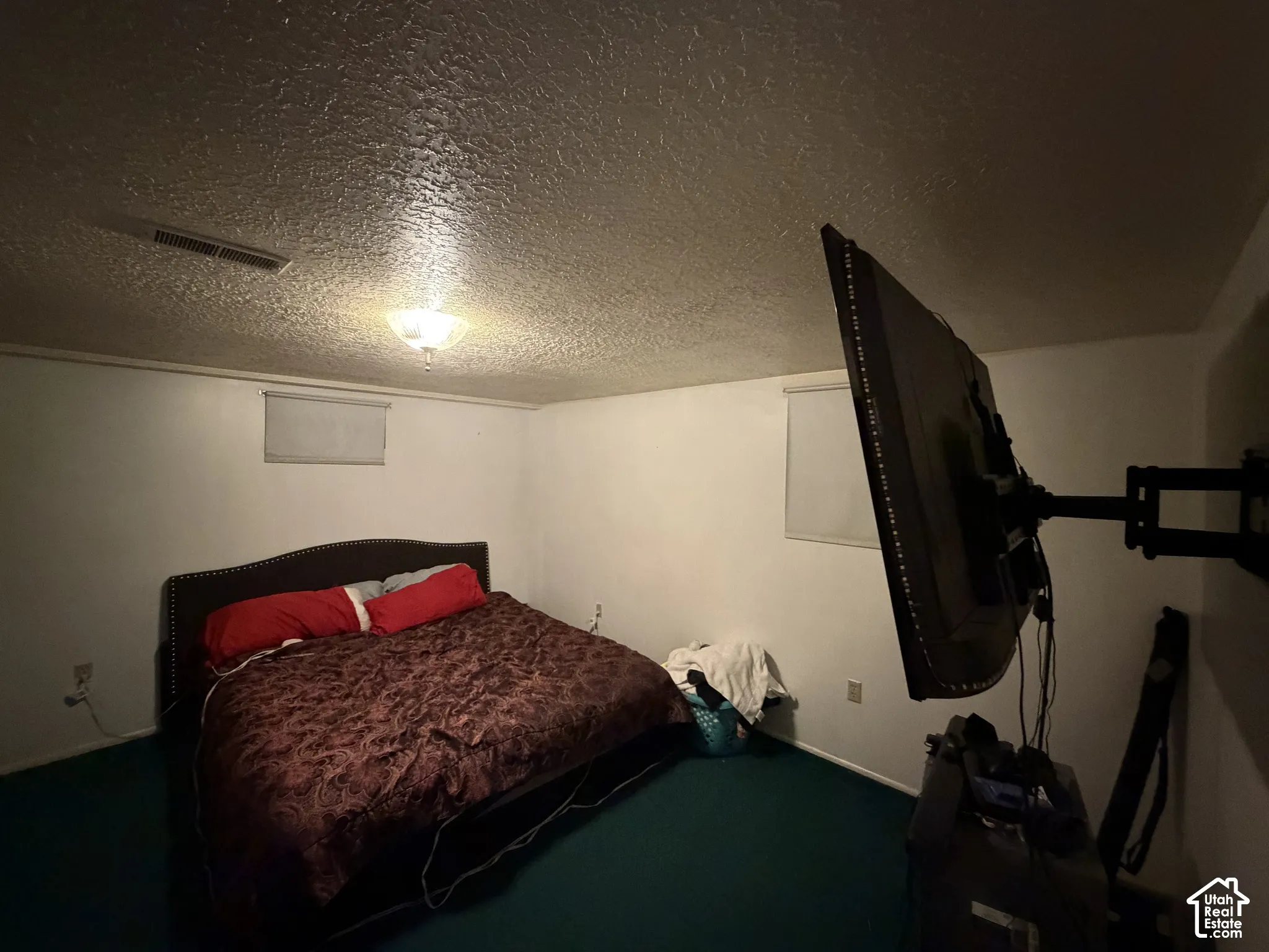 Room featuring a textured ceiling, flush-mount light fixture, and two windows with integrated roller shades