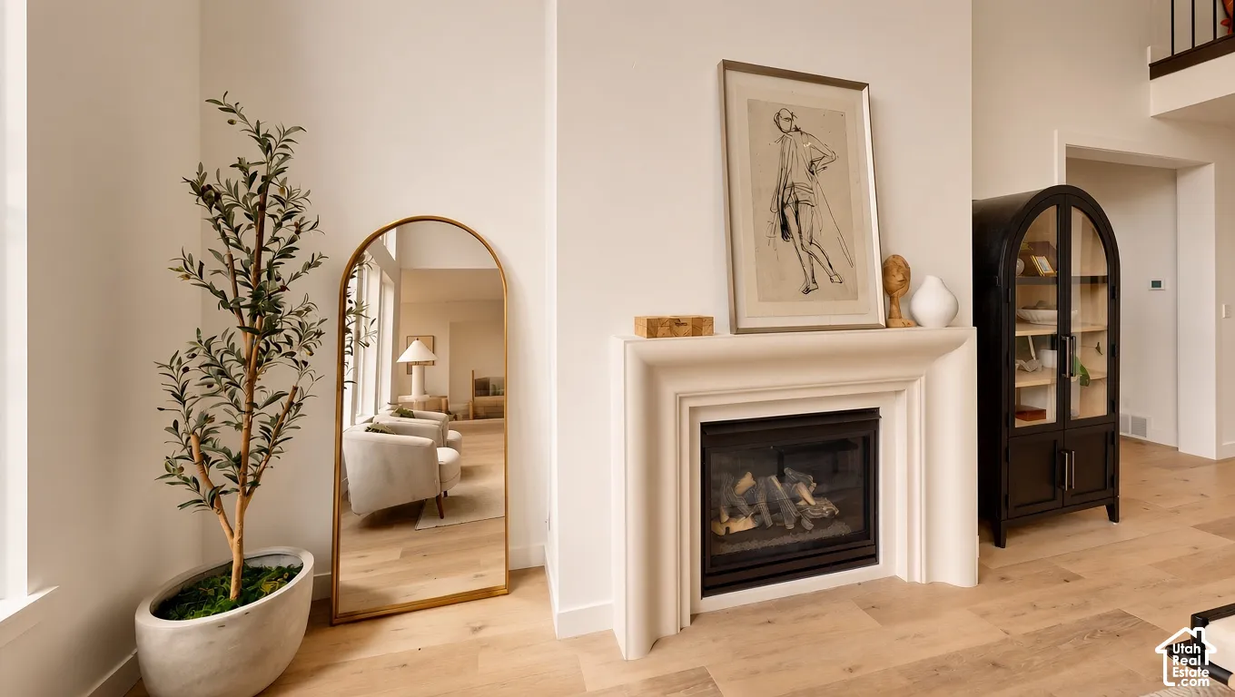 Fireplace with a custom tiered surround, wood-finish flooring, and high ceilings
