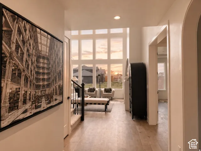 Expansive floor-to-ceiling multi-pane windows, wood-finish flooring, recessed lighting, and arched doorway entry
