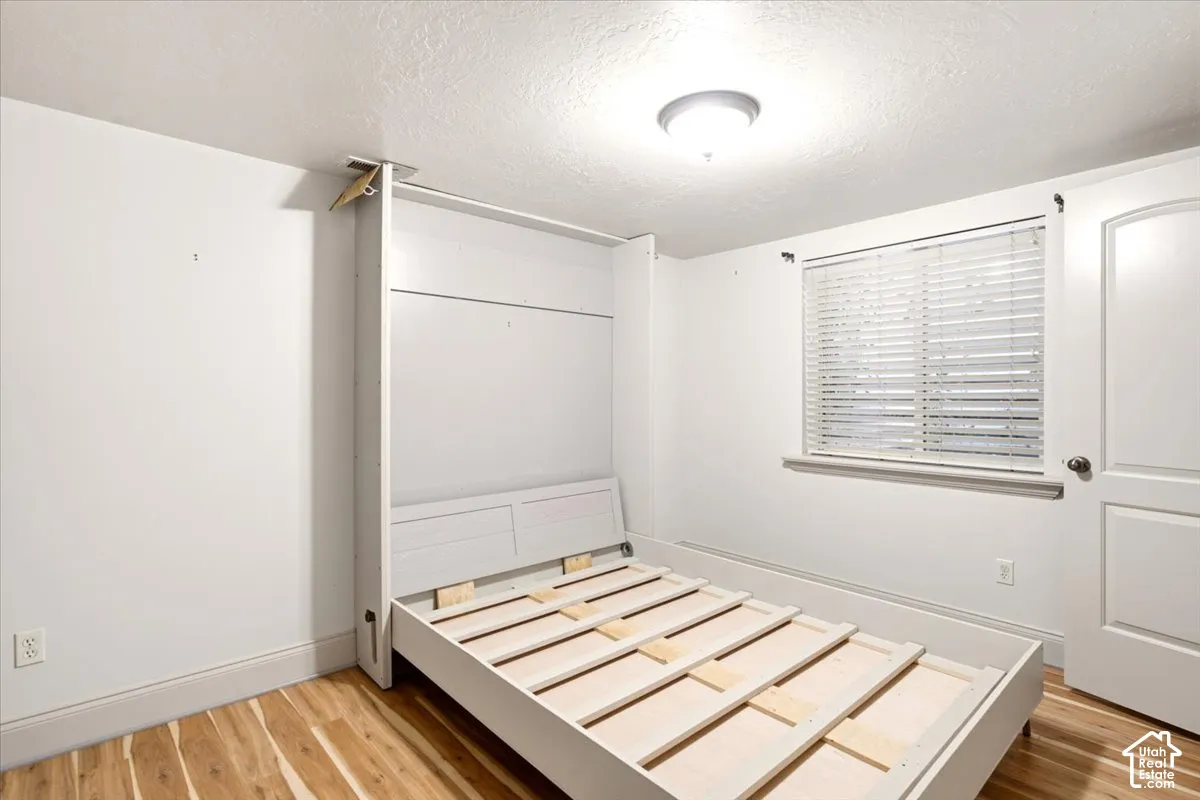 Built-in wall bed unit, wood-finish flooring, horizontal slat blinds, and a paneled interior door