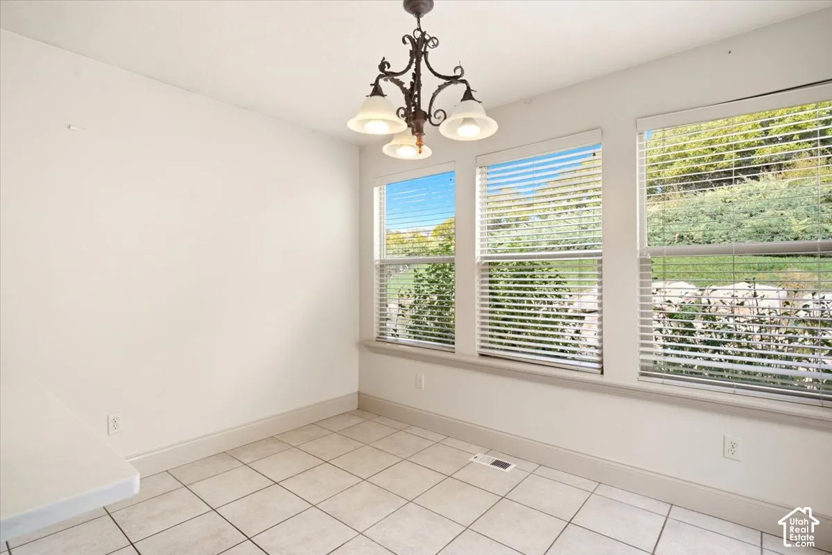 Tile flooring, triple window configuration with horizontal blinds, and a traditional metal chandelier