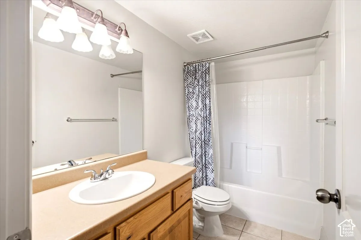 Bathroom featuring a vanity with integrated sink, wood-finish cabinetry, solid-surface countertop, full-width mirror with overhead multi-light fixture, and a tub-shower combination with tiled surround