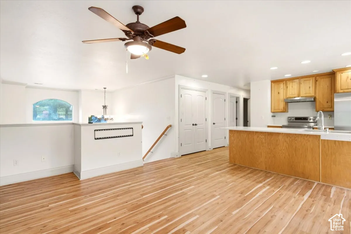 Wood-finish flooring, kitchen featuring natural wood cabinetry and a central island, recessed lighting, and a ceiling fan with integrated light fixture