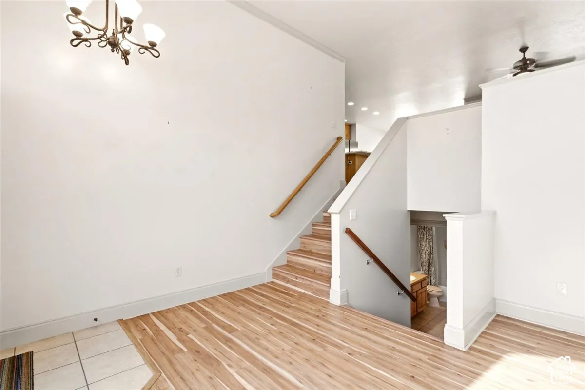 Multi-level floor plan featuring wood-finish flooring, vaulted ceilings, a wrought-iron style chandelier, and wood-toned handrails