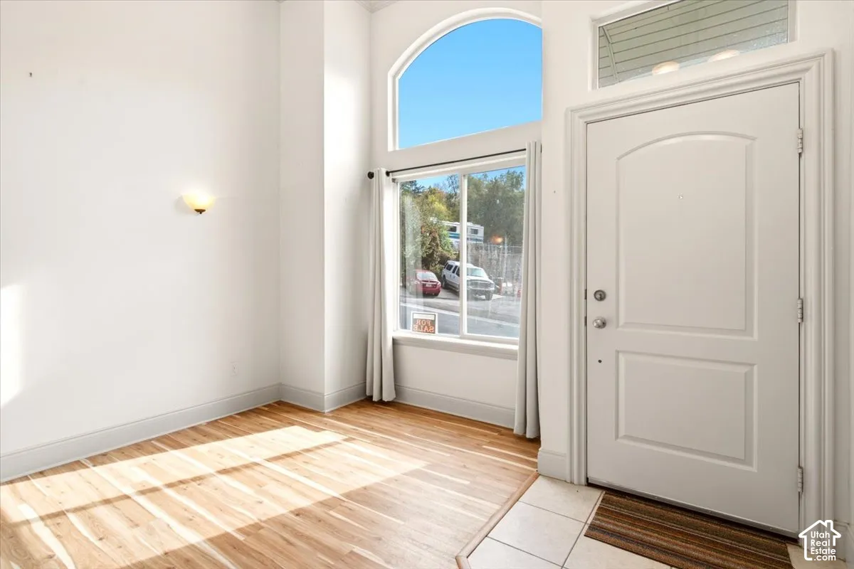 Entryway featuring wood-finish flooring, high ceilings, an arched transom window, and a wall-mounted light fixture